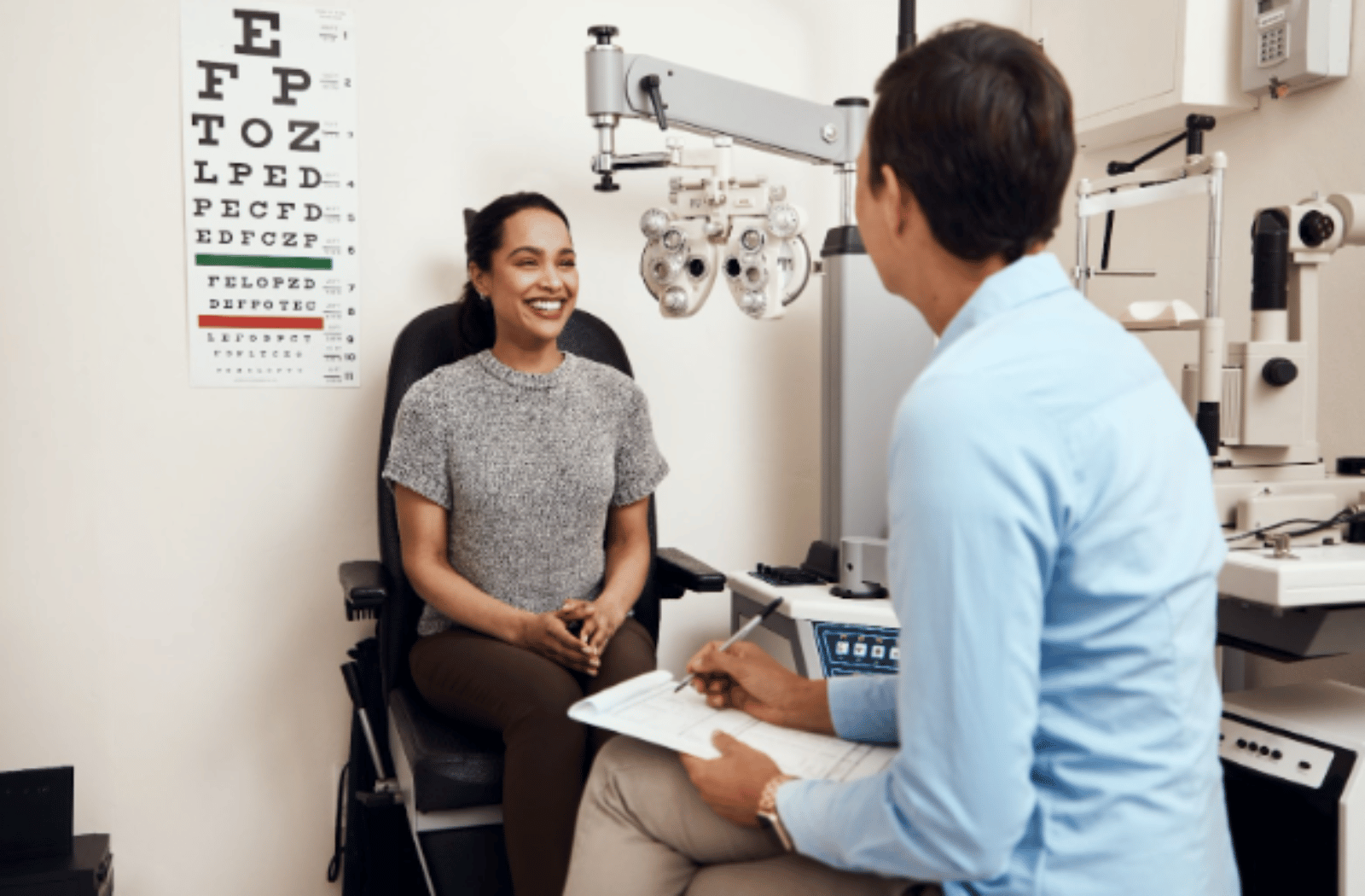 A woman smiles and sits across from her optometrist during an eye exam appointment.