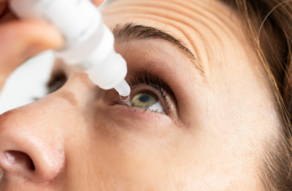 Close-up of a person's eye applying eye drops to treat their dry eye symptoms.